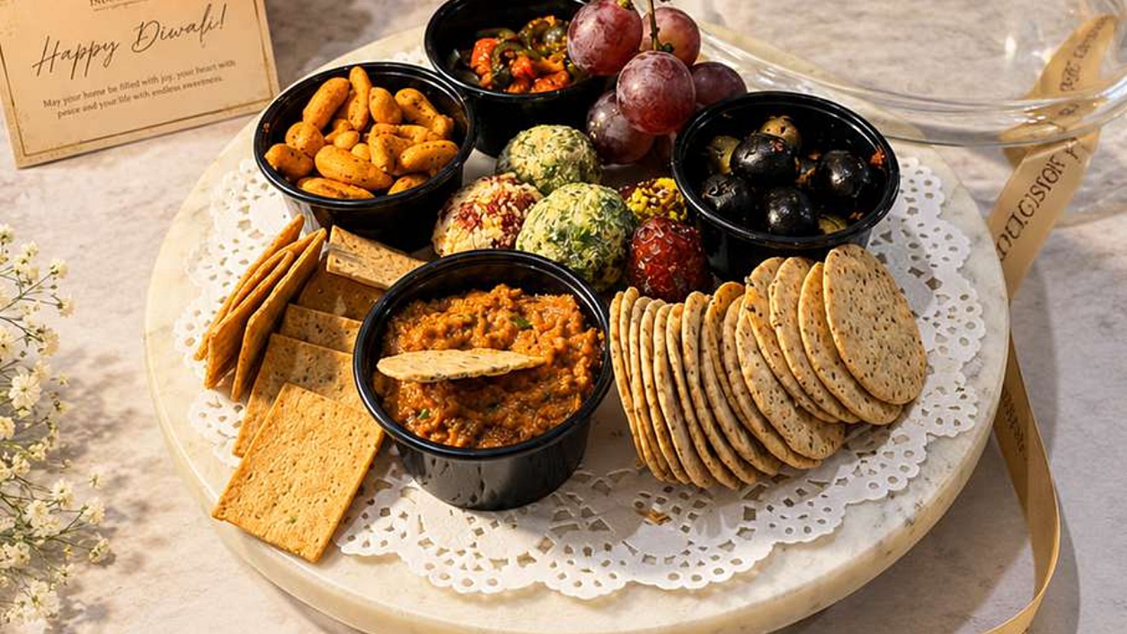 Cheese balls, olives, grapes, cashews, crackers and dips on a marble board