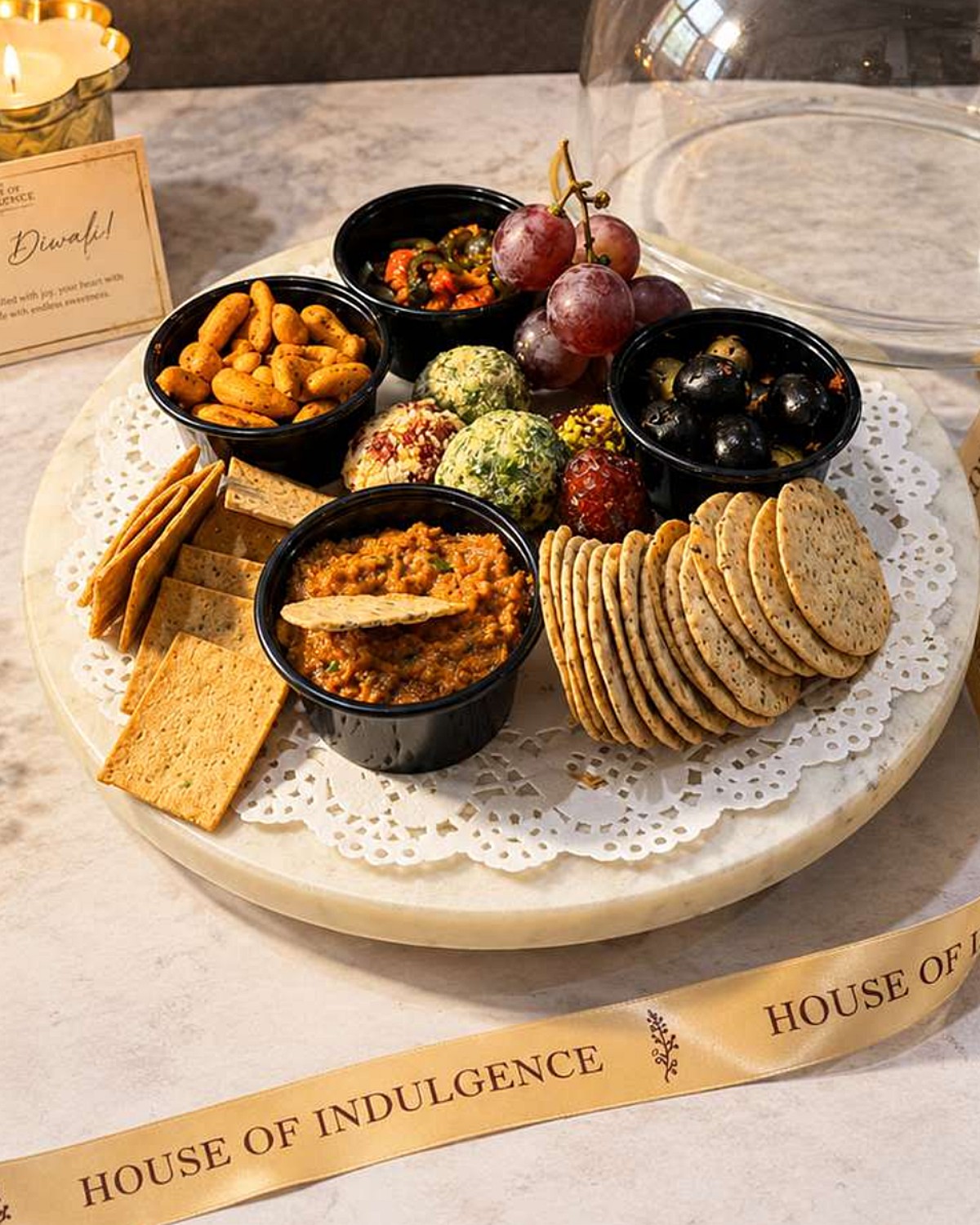 Close-up of cheese balls, olives, grapes, cashews, crackers and dips on a marble board